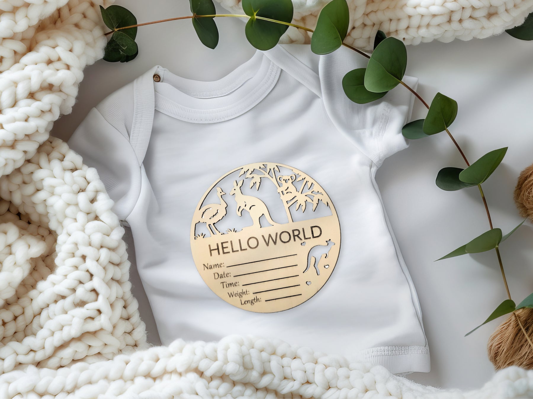 Milestone disc featuring native Australian animals placed on a baby onesie, surrounded by green foliage for a natural, cozy setting.