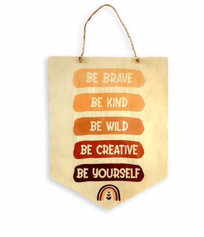 A wooden sign featuring the inspirational phrase "Be Brave, Be Kind, Be Creative, Be Wild, Be Yourself." The sign showcases a warm, natural finish and is displayed against a plain background, emphasising its message and craftsmanship.