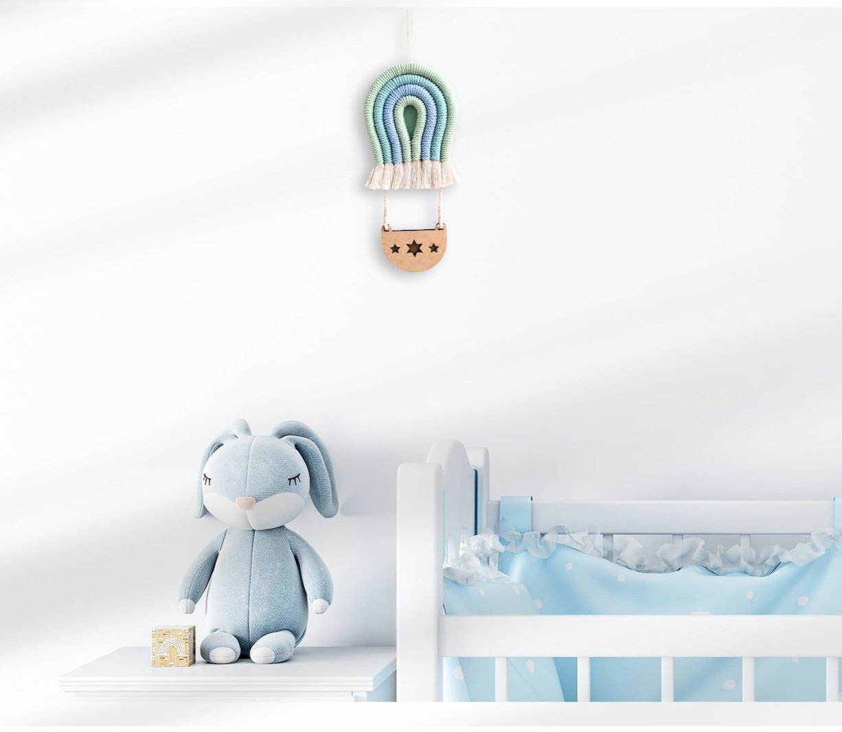 Blue and green Macramé Hot Air Balloon hanging on the wall in a blue-themed nursery, styled with a blue bunny toy and cozy blanket.