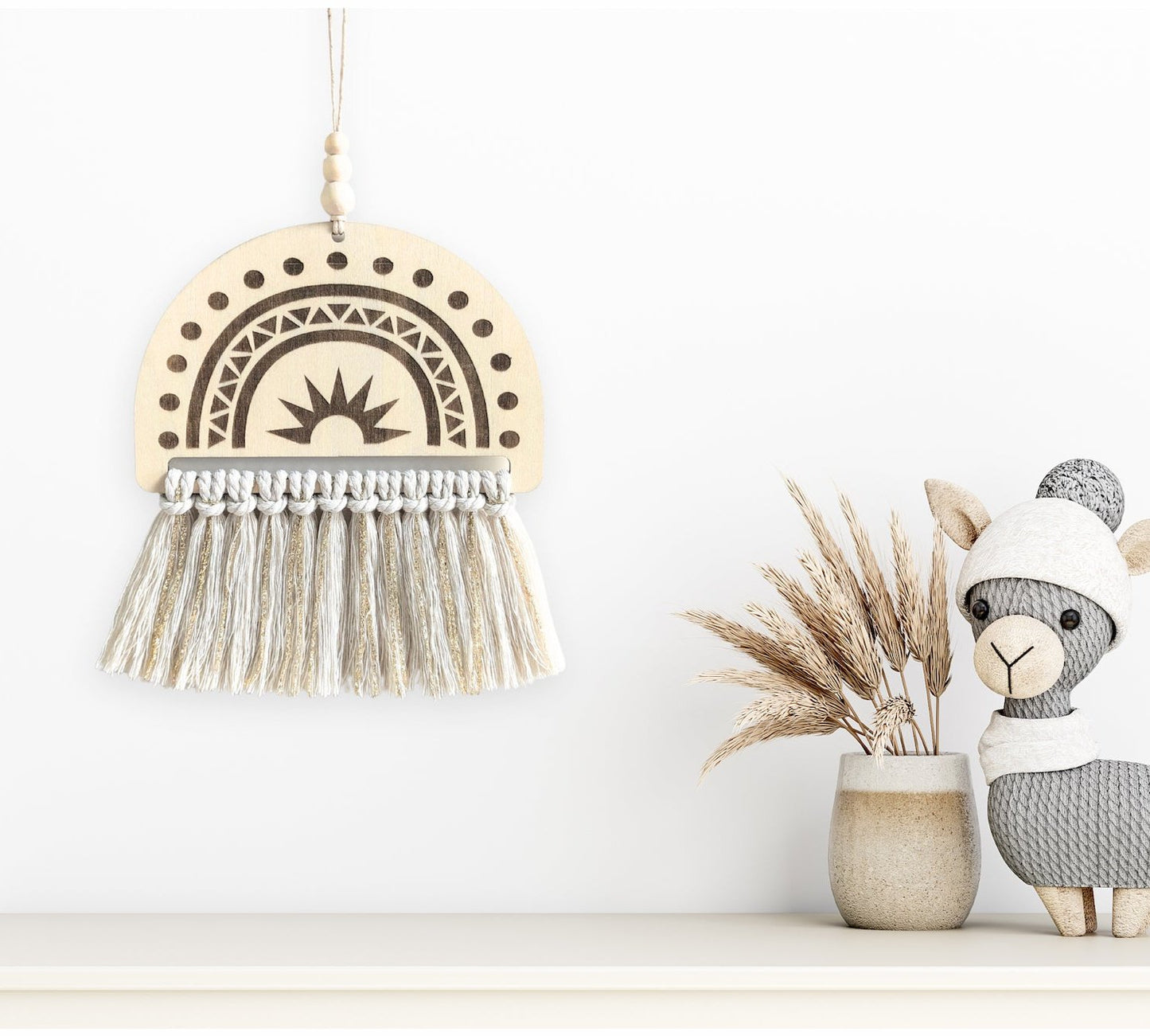 Rainbow Macramé Wall Art in natural white and gold tassels, hanging on a wall next to a small sheep statue and dried wheat for a rustic, cozy display.