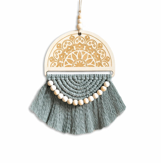 A handcrafted wooden semicircle macrame wall hanging in sage green, with delicate beading, set against a plain background.