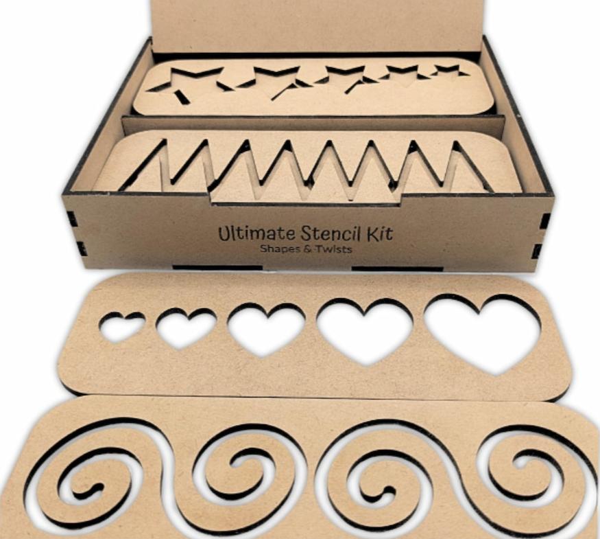 Close-up of the Ultimate Stencil Set with the box open, showing two stacks of stencils—at the front of the box lays one with a heart-shaped stencil and the other with a swirling shape stencil—displayed on a plain background